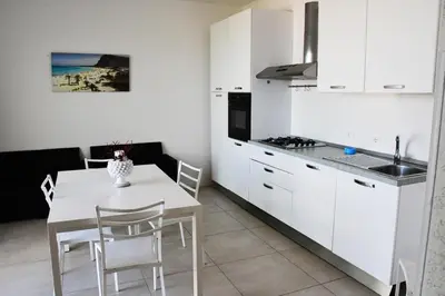 a kitchen with white cabinets and a white table and chairs at Villa Luxury Fronte mare San Vito lo Capo in San Vito lo Capo