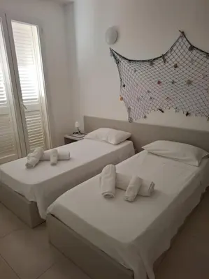 two beds in a bedroom with white sheets and pillows at Villa Luxury Fronte mare San Vito lo Capo in San Vito lo Capo