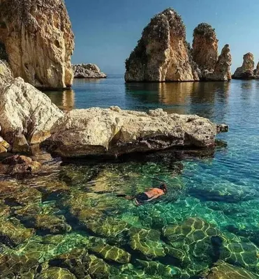a person laying in the water near some rocks at Casa Gerani in Castellammare del Golfo