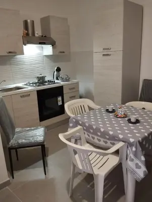 a kitchen with a table and chairs and a kitchen with a stove at Casa Gerani in Castellammare del Golfo