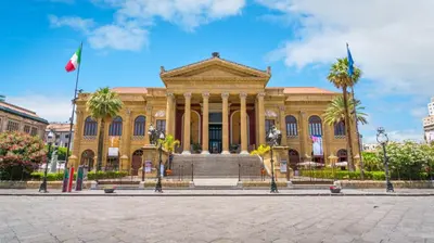 a large building with palm trees in front of it at Elegante Appartamento Palermo in Palermo