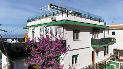 a white building with a flowering tree in front of it at Addaura Luxury Apartment in Palermo