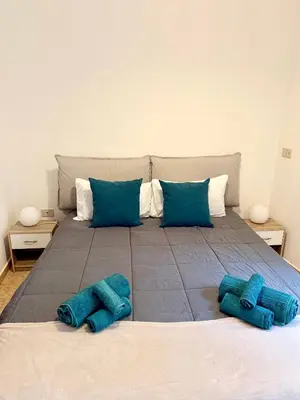 a large bed with two blue pillows on it at Gigi's Apartment in Palermo