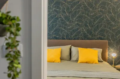 a bed with two yellow pillows and a wallpaper at Politeama Luxury Suite in Palermo
