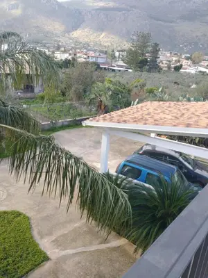 a car parked on the side of a house with a palm tree at Carini house in Carini