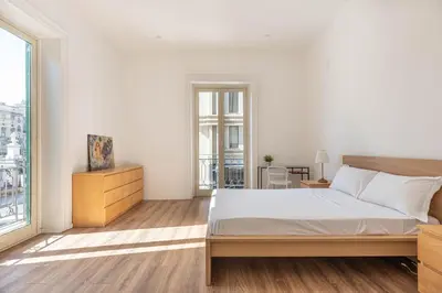 a white bedroom with a bed and a large window at Turati Apartment al Politeama by Wonderful Italy in Palermo