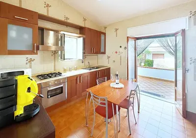a kitchen with a wooden table and a dining room at Solemar Sicilia - Ville Paradiso in Santa Flavia