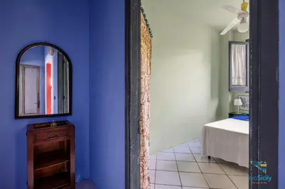 a blue room with a mirror and a bed at Verosicily Panoramic House with access to the sea in Terrasini