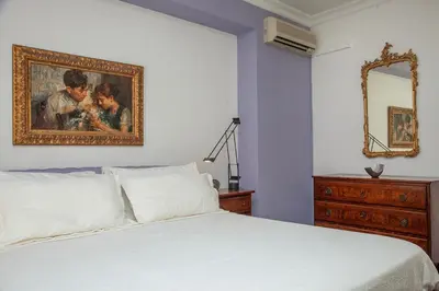a bedroom with a white bed and a painting on the wall at Casa Adele in Palermo