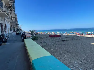 a beach with people on the sand and the ocean at Una Finestra sul Mare in Palermo
