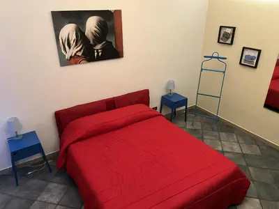a bedroom with a red bed and a painting on the wall at Le Stanze di Magritte in Palermo