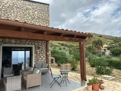 a patio with a wooden pergola and a table and chairs at Stella Del Mare in Scopello