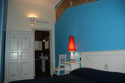a blue bedroom with a bed and a red lamp at Locanda Del Drago in Monreale