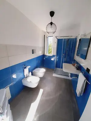 a blue and white bathroom with two sinks and a toilet at Campofelice Holidays East Villa in Campofelice di Roccella