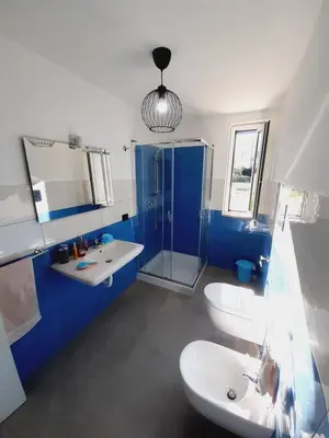 a blue and white bathroom with two sinks and a shower at Campofelice Holidays East Villa in Campofelice di Roccella