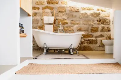 a bath tub in a bathroom with a stone wall at Duplex Townhouse with Gigantic Terrace in Palermo