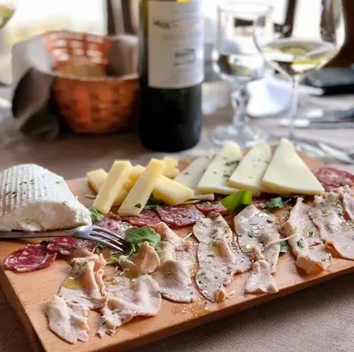 a cutting board with meat and cheese and a bottle of wine at Agriturismo Tenute Pispisa Segesta in Calatafimi