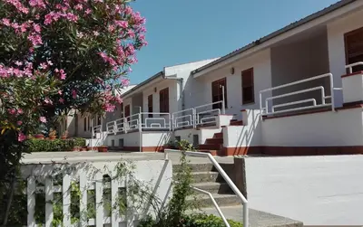 a building with stairs and a tree with pink flowers at Bellavista Apartments in Scopello
