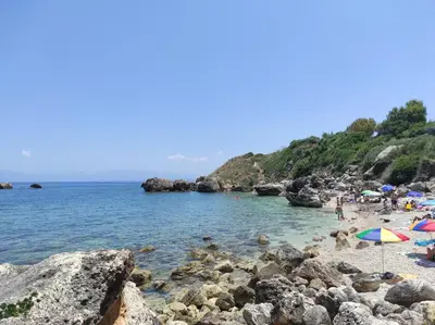a group of people on a beach with umbrellas at Bellavista Apartments in Scopello