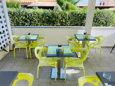 a row of tables and yellow chairs on a patio at B&b Diamond in San Vito lo Capo