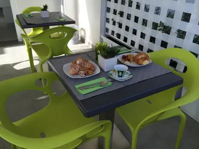 a table with two green chairs and food on it at B&b Diamond in San Vito lo Capo