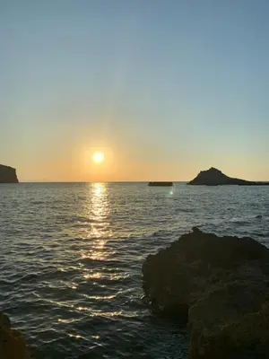 a sunset over the ocean with rocks in the water at Casa Vacanze La Dolce Vita in Terrasini