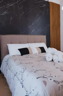 a bed with white pillows and a black wall at Butera 505-Luxury Suites in Bagheria