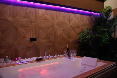 a bathroom with a white bath tub with a wooden wall at Spera Luxury Palermo & SPA in Palermo