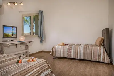 a bedroom with two beds and a table and a window at Borgo Aranci - Villa Nicales in Castellammare del Golfo