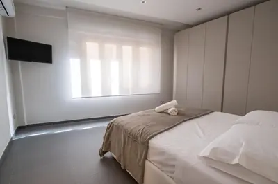 a white bedroom with a bed and a window at Teatro Apartments Villafranca in Palermo
