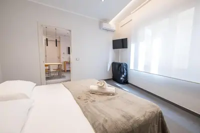 a white bedroom with a bed with a towel on it at Teatro Apartments Villafranca in Palermo