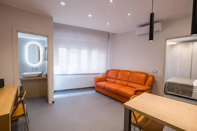 a living room with an orange couch and a bed at Teatro Apartments Villafranca in Palermo
