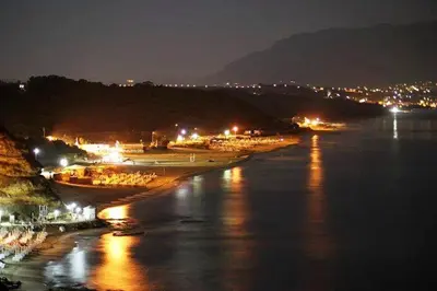 a beach at night with lights on the water at Casa Vacanze Nicole in Balestrate