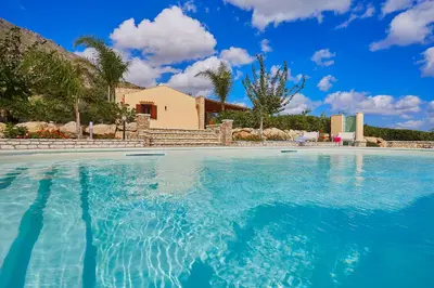 a swimming pool with blue water in front of a house at Villa Ninetta in Scopello