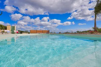 a large swimming pool with a blue sky and clouds at Villa Ninetta in Scopello