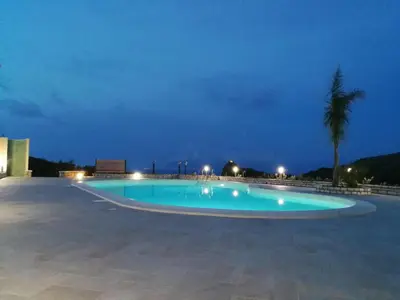 a large swimming pool at night with a palm tree at Villa Ninetta in Scopello