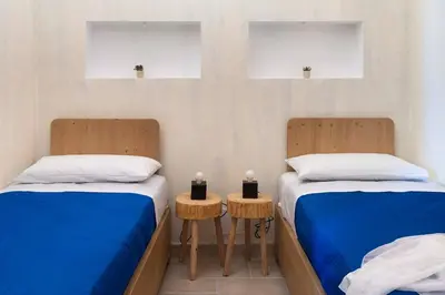 two beds in a room with blue sheets and white pillows at Villa Guidaloca Cala Bianca in Castellammare del Golfo