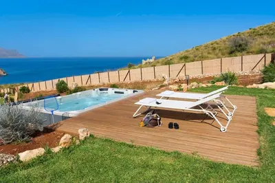 a picnic table on a deck next to a pool at Villa Guidaloca Cala Bianca in Castellammare del Golfo