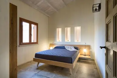 a bedroom with a bed with a blue comforter and a window at Villa Scogliera Cala Bianca in Castellammare del Golfo