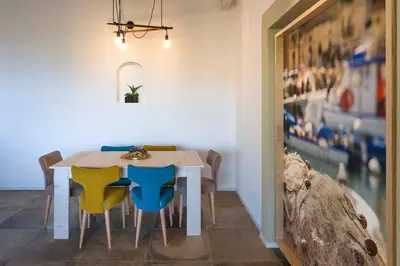 a dining room with a white table and chairs at Villa Scogliera Cala Bianca in Castellammare del Golfo