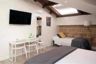 a bedroom with a bed and a desk and a tv at B&B Cannoli in Palermo