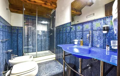 a blue tiled bathroom with a toilet and a sink at 1 Bedroom Stunning Home In Partinico in Partinico