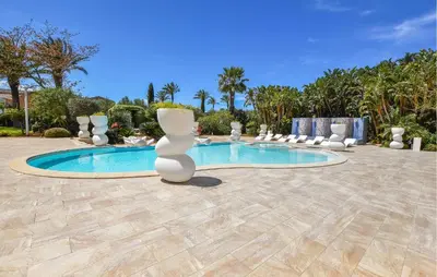 a resort pool with white chairs and trees at 1 Bedroom Stunning Home In Partinico in Partinico