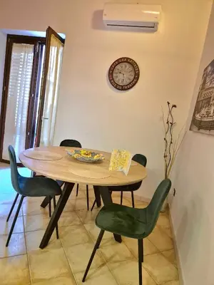 a dining room table with chairs and a clock on the wall at Patania Royal Apartment in Palermo