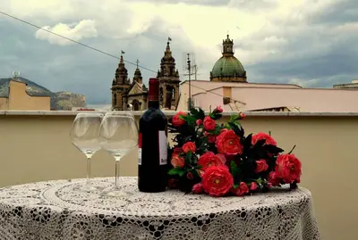 a table with two wine glasses and a bouquet of roses at Patania Royal Apartment in Palermo