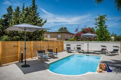 a pool with chairs and umbrellas next to a fence at Trinacrys - Casa Vacanze in Alcamo