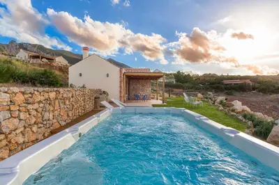 a pool in the backyard of a house with a stone wall at Villa Ancora Cala Bianca in Castellammare del Golfo