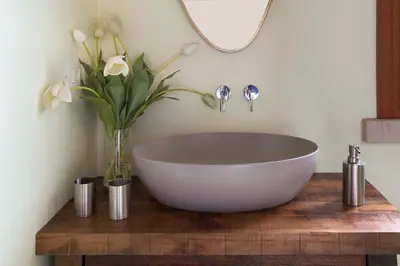 a bathroom with a white bowl on a wooden table with flowers at Villa Ancora Cala Bianca in Castellammare del Golfo