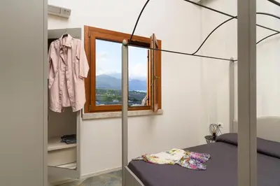 a bedroom with a bed and a window and a clothes rack at Villa Ancora Cala Bianca in Castellammare del Golfo
