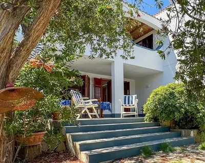 a house with blue and white chairs and stairs at Villa Sao Scopello Punta Pispisa in Scopello